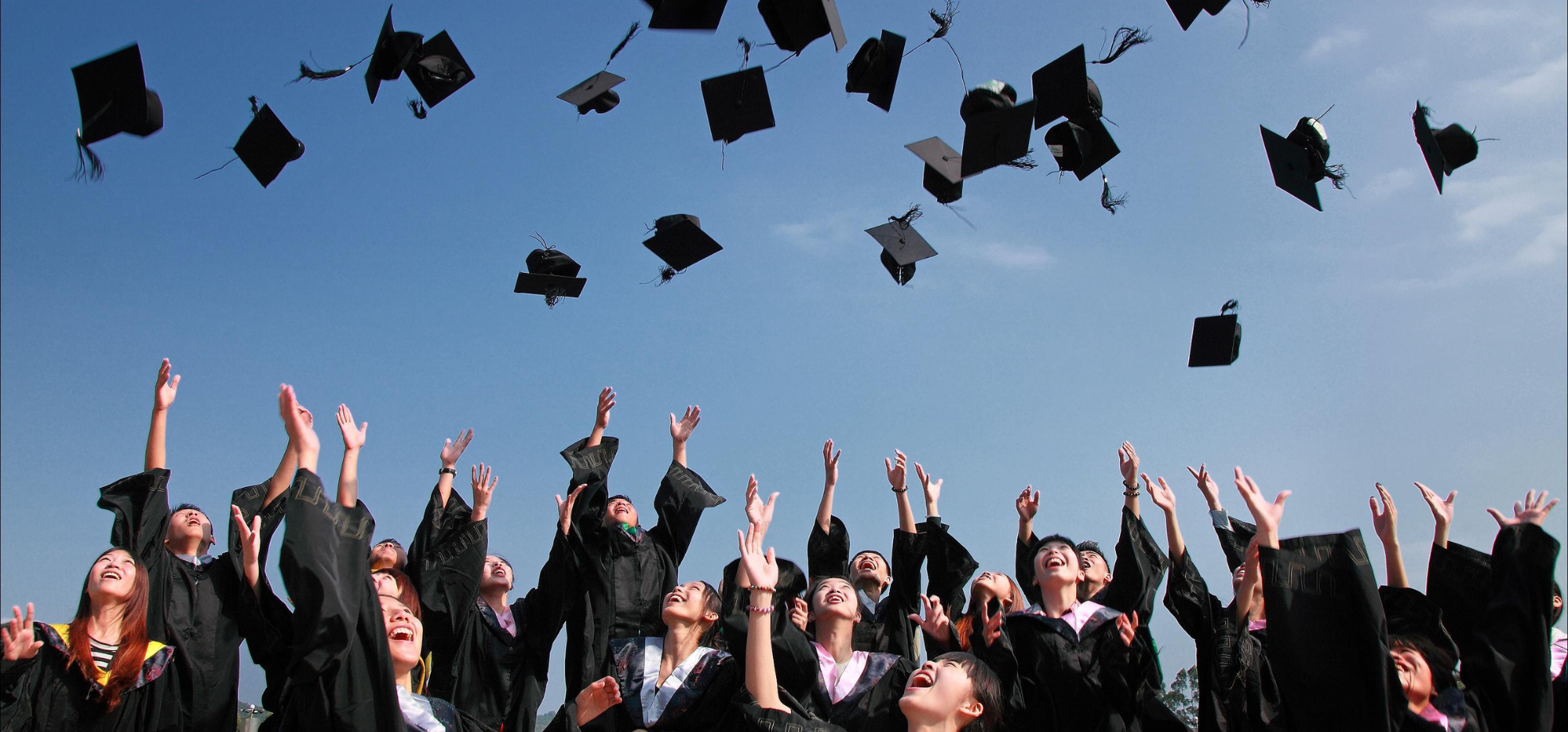Image of graduates throwing their caps in the air.