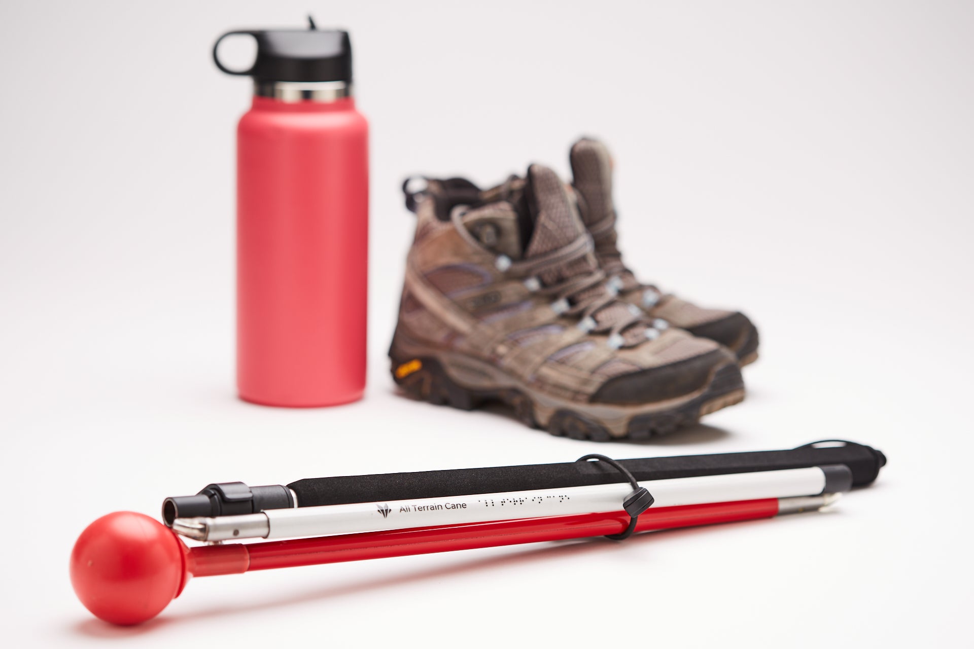 Image of the All Terrain Cane from Awarewolf Gear next to hiking boots.