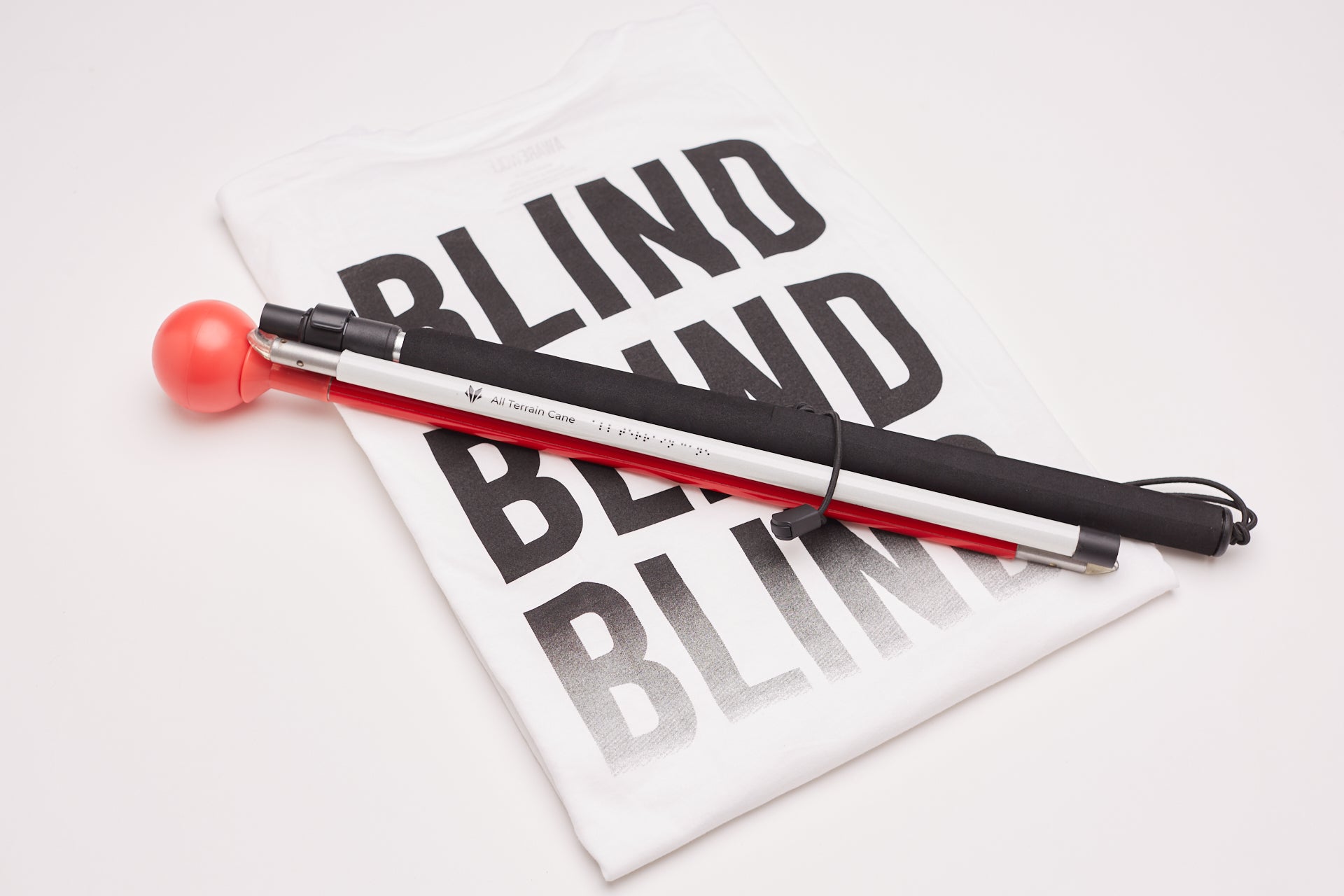 Image of the All Terrain Cane in front of a banner reading the word "Blind" three times.