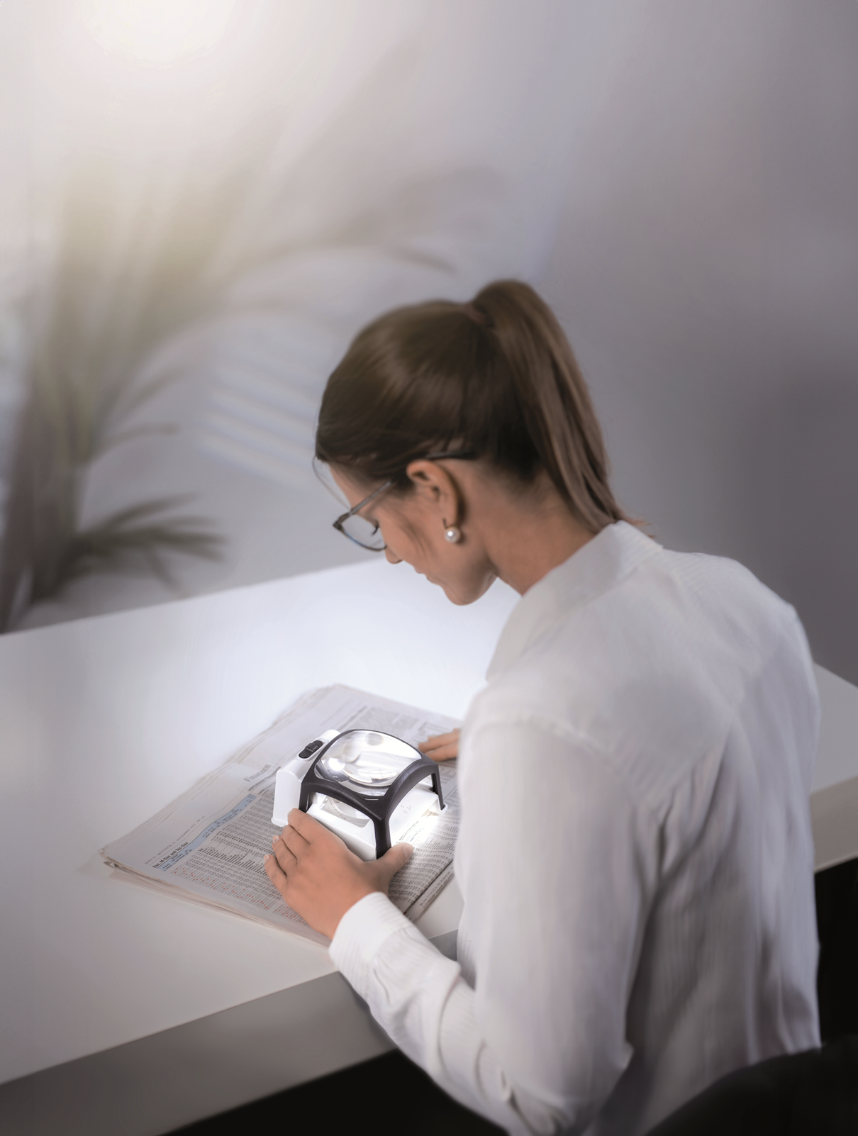 Image of of a woman using the TWIN-Lux LED 3.5x stand magnifier from Schweizer.