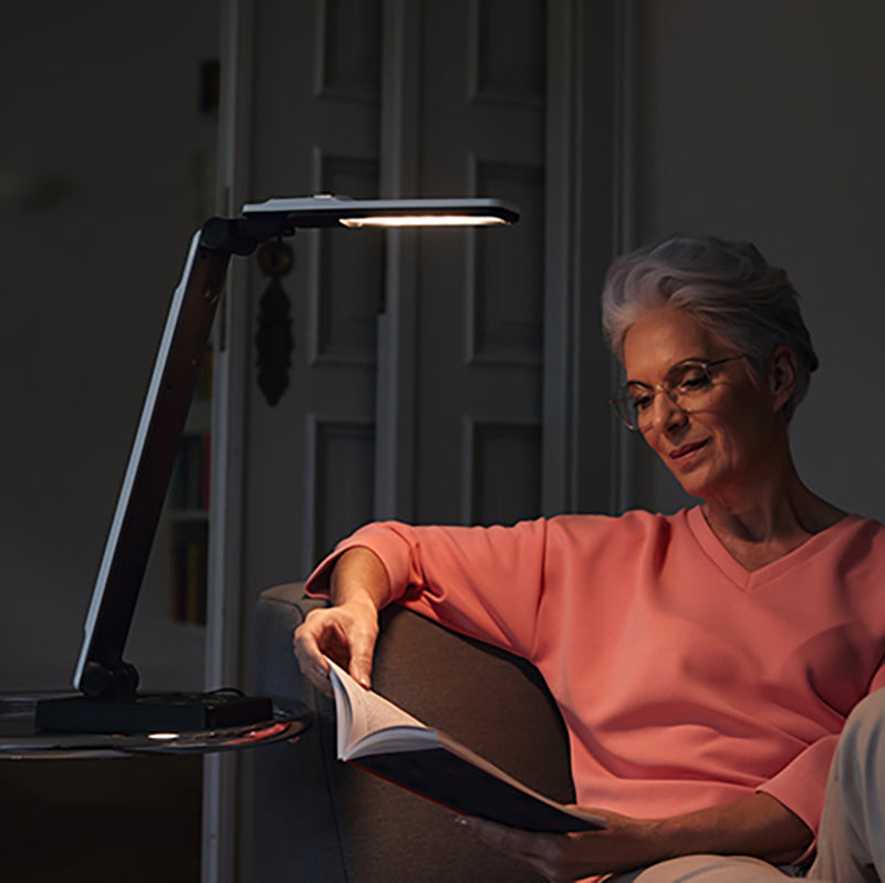 Image of a man using the Elumentis LED Desk Lamp as a reading light.