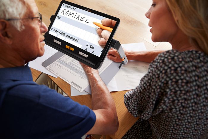 Image of a man and woman using the explorē 12 with the stand to read and sign a document.